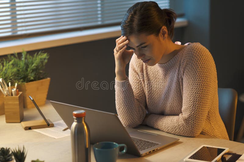 Tired woman with headache working with a laptop royalty free stock image