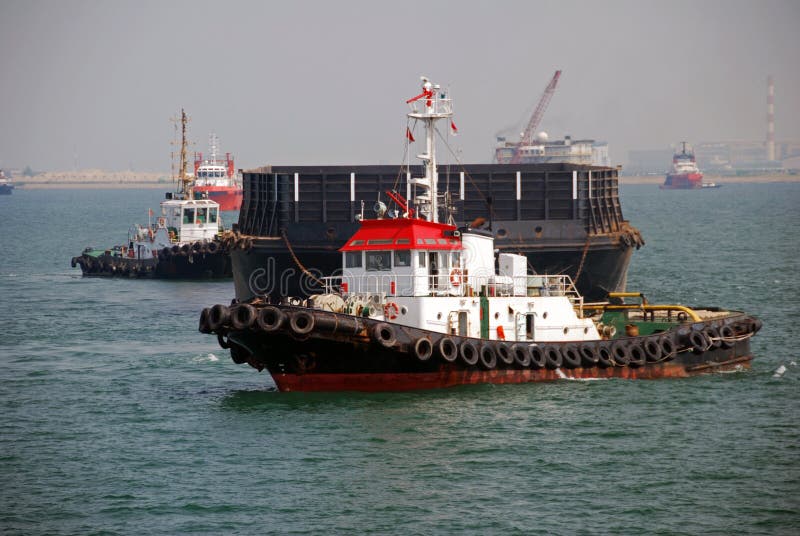 A small tug seen towing a large barge in Singapore anchorage. A small tug seen towing a large barge in Singapore anchorage.