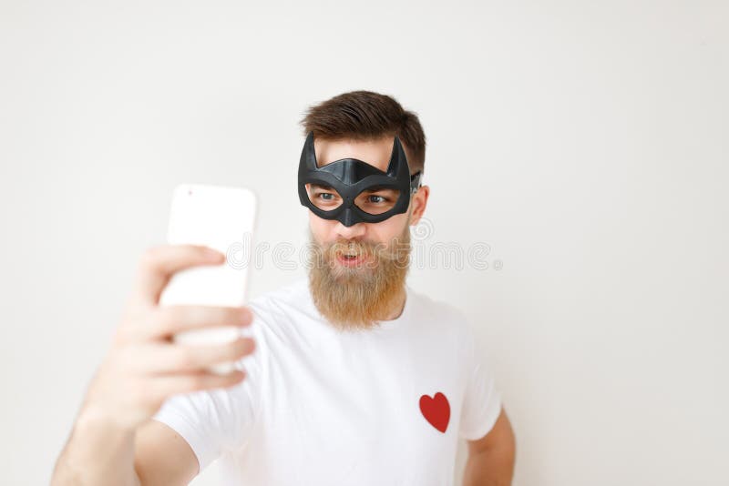 Tiro aislado del varón atractivo con la cara larga gruesa de las cubiertas de la barba y del bigote con la máscara del ayudante p imagenes de archivo Tiro aislado del varón atractivo con la cara larga gruesa de las cubiertas de la barba y del bigote con la máscara del ayudante p imagenes de archivo