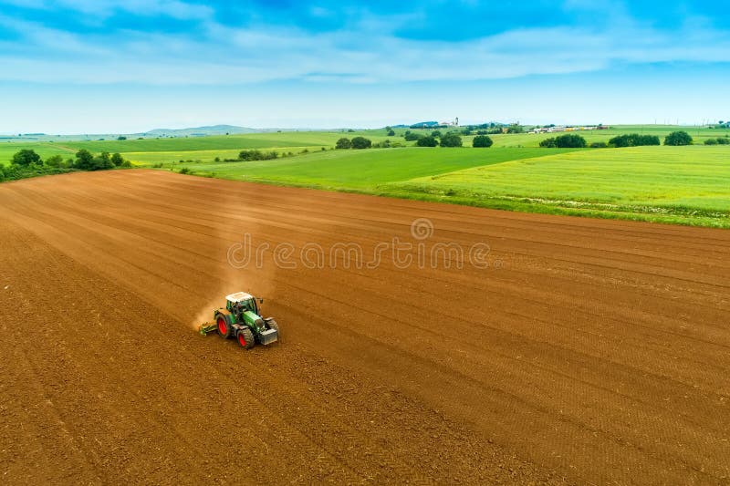 Tiro aéreo do fazendeiro com um trator no campo agrícola imagem de stock Tiro aéreo do fazendeiro com um trator no campo agrícola imagem de stock