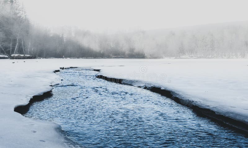 Tiro bonito do lago enevoado no norte com gelo no lado Lago nevoento pequeno no tempo de inverno com watter de fluxo azul de cris fotografia de stock Tiro bonito do lago enevoado no norte com gelo no lado Lago nevoento pequeno no tempo de inverno com watter de fluxo azul de cris fotografia de stock