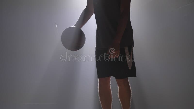 Tiro cercano de las piernas del ` s del hombre que gotean la bola en sitio brumoso con el reflector metrajes