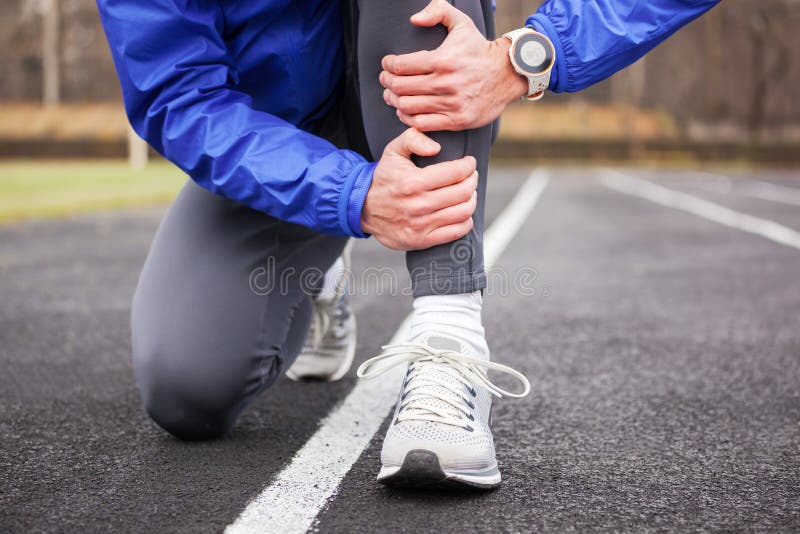 Tiro cosechado de un corredor joven que lleva a cabo su pierna en dolor