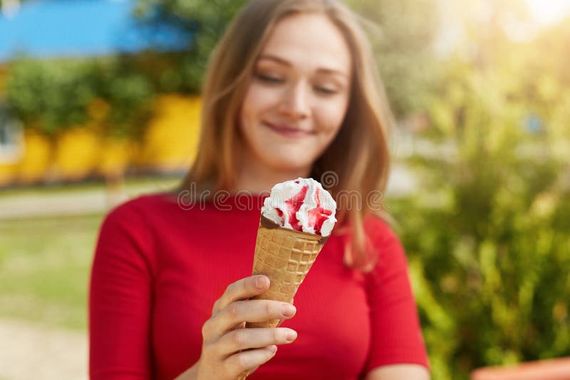 Tiro cosechado del helado delicioso en manos del ` s de la muchacha La hembra joven se vistió en la ropa roja que sostenía el hel imagen de archivo Tiro cosechado del helado delicioso en manos del ` s de la muchacha La hembra joven se vistió en la ropa roja que sostenía el hel imagen de archivo