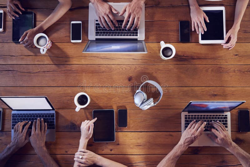 Tiro de arriba de adultos jovenes usando tecnología en una tabla imagen de archivo libre de regalías Tiro de arriba de adultos jovenes usando tecnología en una tabla imagen de archivo libre de regalías