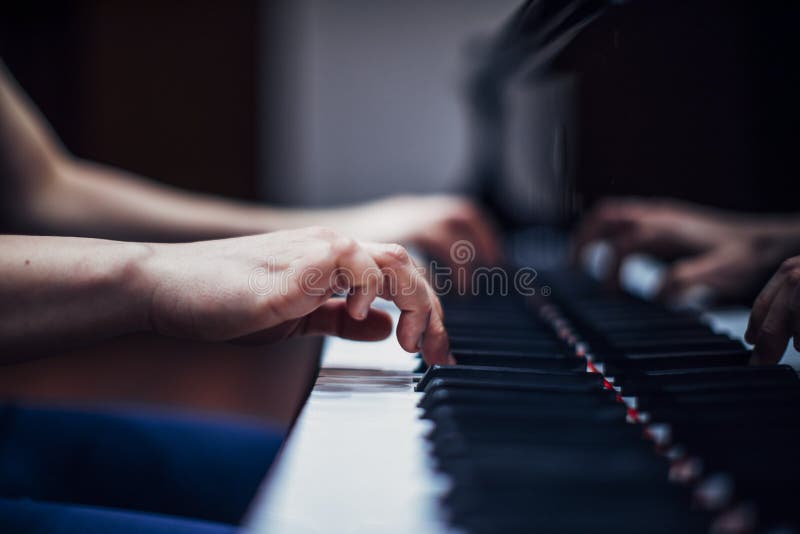 homem asiático usando fones de ouvido brancos toca piano e canta