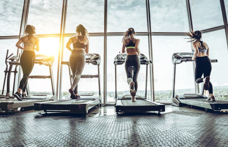 Tiro de quatro mulheres que movimentam-se na escada rolante no health club fotos de stock Tiro de quatro mulheres que movimentam-se na escada rolante no health club fotos de stock