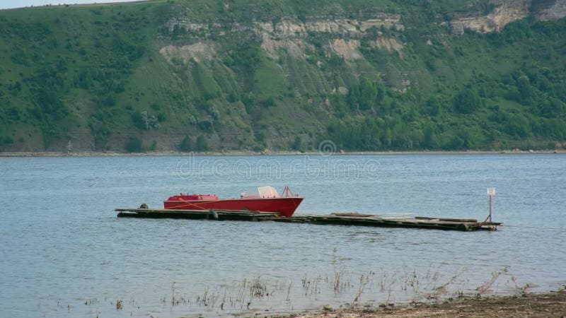 Tiro del pequeño bote de salvamento rojo en el río contra la montaña con el bosque