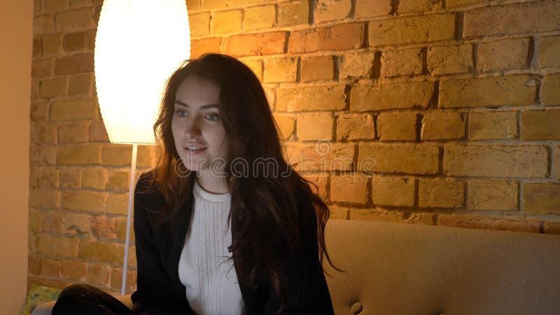Tiro del primo piano di giovane TV di sorveglianza femminile caucasica graziosa con curiosità e pensosità che sorridono mentre se immagini stock libere da diritti Tiro del primo piano di giovane TV di sorveglianza femminile caucasica graziosa con curiosità e pensosità che sorridono mentre se immagini stock libere da diritti