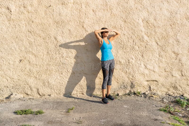 Tiro do corredor do ajuste que está contra uma parede fora Mulher desportiva que relaxa após exercício running fotos de stock Tiro do corredor do ajuste que está contra uma parede fora Mulher desportiva que relaxa após exercício running fotos de stock