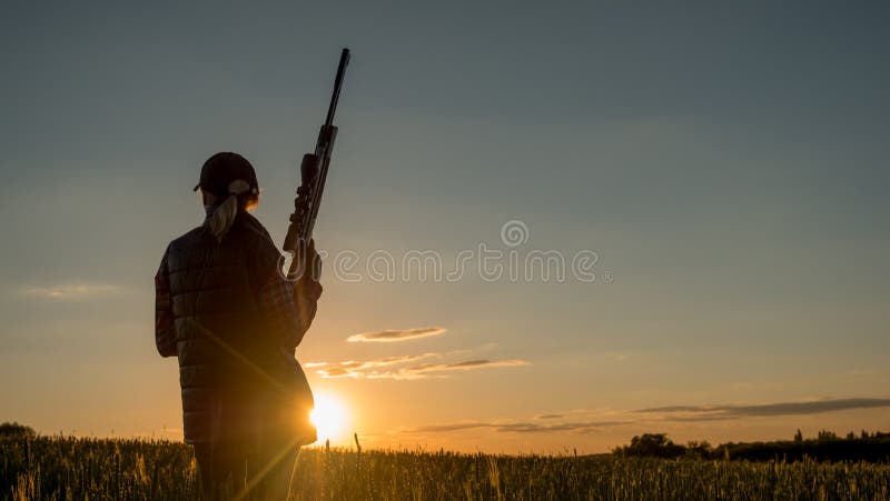Tiro do esporte e caça - mulher com um rifle no por do sol foto de stock royalty free Tiro do esporte e caça - mulher com um rifle no por do sol foto de stock royalty free