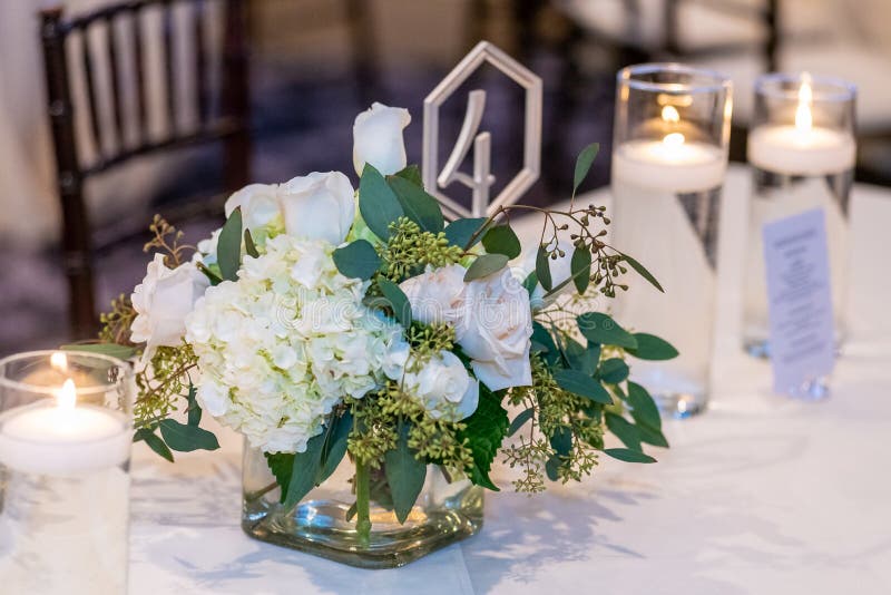 A closeup shot of a beautiful bouquet with white roses and hortensias on the wedding table number 4. A closeup shot of a beautiful bouquet with white roses and hortensias on the wedding table number 4