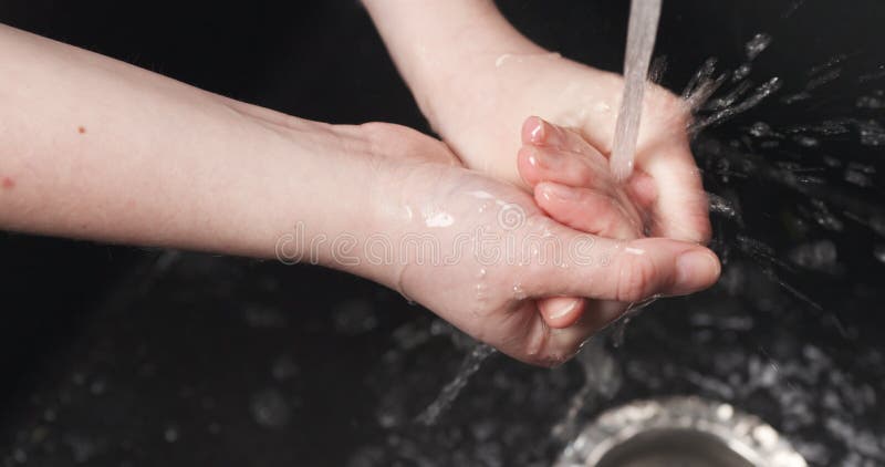 Tiro Handheld da menina que lava suas mãos sob o volume de água do torneira imagens de stock Tiro Handheld da menina que lava suas mãos sob o volume de água do torneira imagens de stock