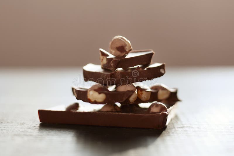 Tiro horizontal da tabela marrom com chocolate, pyramide feito a mão das partes do chocholate isoladas sobre a superfície escura, foto de stock royalty free Tiro horizontal da tabela marrom com chocolate, pyramide feito a mão das partes do chocholate isoladas sobre a superfície escura, foto de stock royalty free