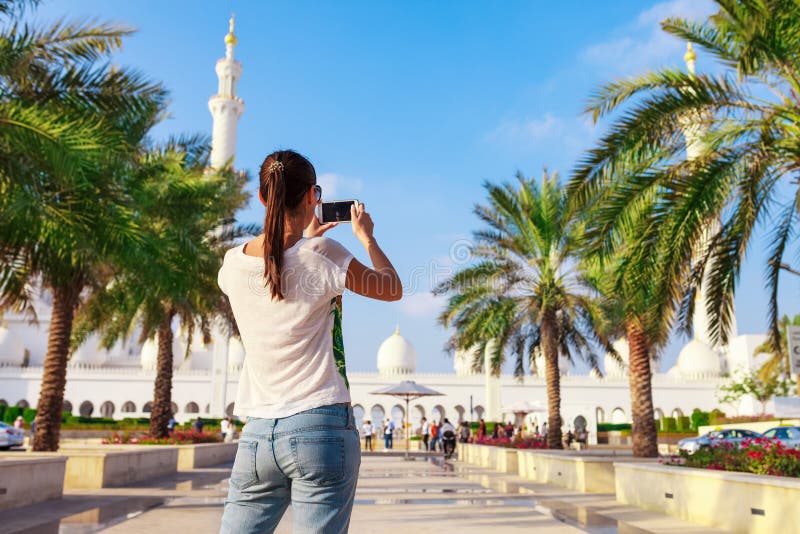 Tiroteo tur?stico joven de la mujer en mezquita blanca de Sheikh Zayed del tel?fono m?vil la gran en Abu Dhabi, United Arab Emira fotografía de archivo libre de regalías Tiroteo tur?stico joven de la mujer en mezquita blanca de Sheikh Zayed del tel?fono m?vil la gran en Abu Dhabi, United Arab Emira fotografía de archivo libre de regalías
