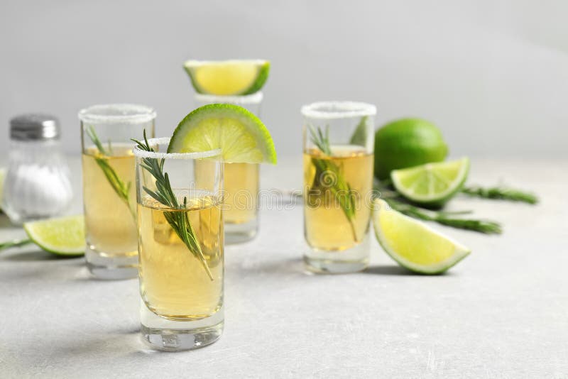 Tirs d'or de tequila avec les tranches juteuses de chaux image stock Tirs d'or de tequila avec les tranches juteuses de chaux image stock