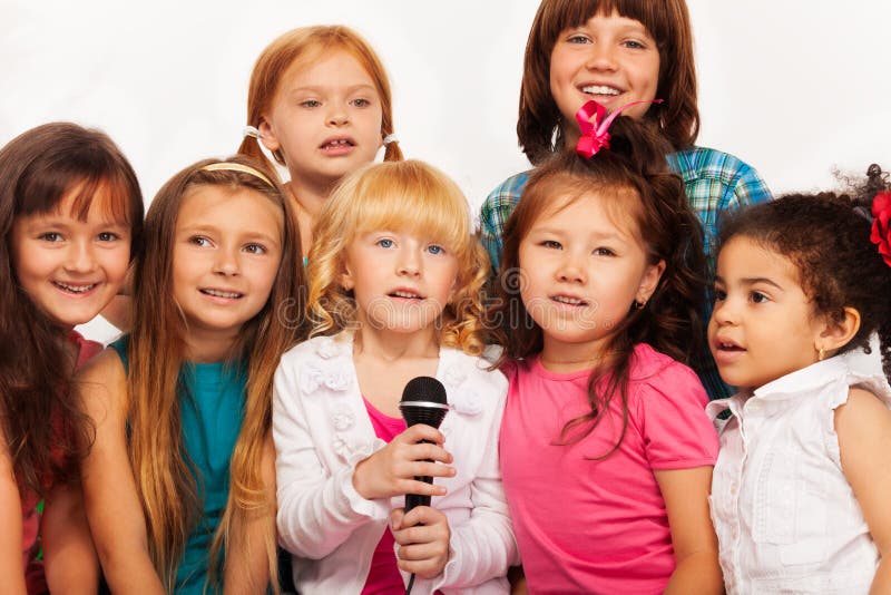 Close-up shoot of a large group of five happy little kids, boys and girls, singing together sitting to microphone on the coach at home. Close-up shoot of a large group of five happy little kids, boys and girls, singing together sitting to microphone on the coach at home