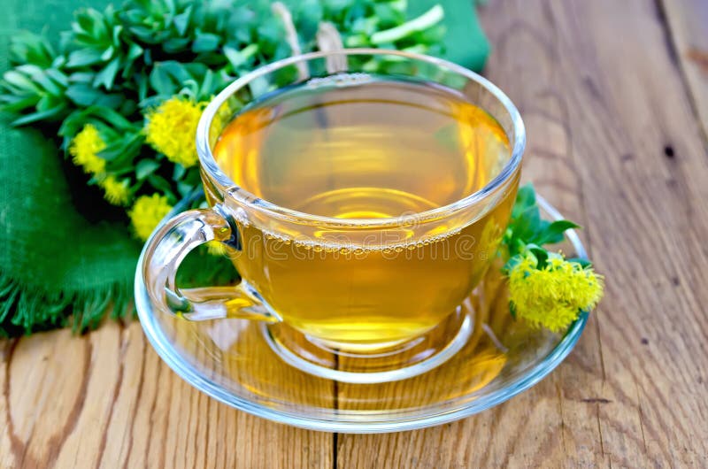 Tisane dans une tasse avec un bouquet de rosea de Rhodiola sur le verrat photos stock Tisane dans une tasse avec un bouquet de rosea de Rhodiola sur le verrat photos stock