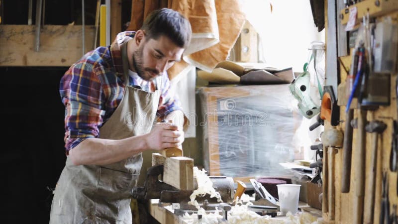 Tischler, der mit Fläche und Holz an der Werkstatt arbeitet