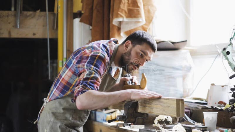 Tischler, der mit Fläche und Holz an der Werkstatt arbeitet