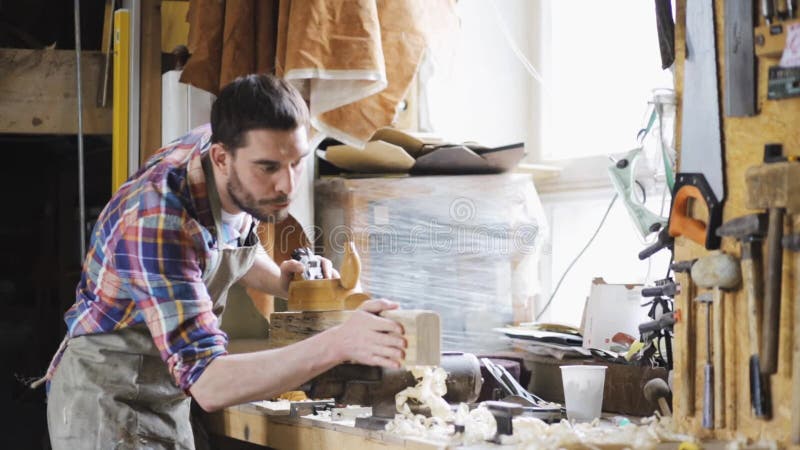 Tischler, der mit Fläche und Holz an der Werkstatt arbeitet