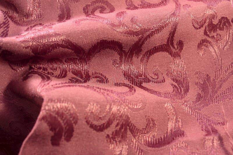 Deep burgundy colored damask fabric shows the stitches of the satin leaf tone on tone pattern. There are some soft folds in the fabric creating light and dark areas. Deep burgundy colored damask fabric shows the stitches of the satin leaf tone on tone pattern. There are some soft folds in the fabric creating light and dark areas.