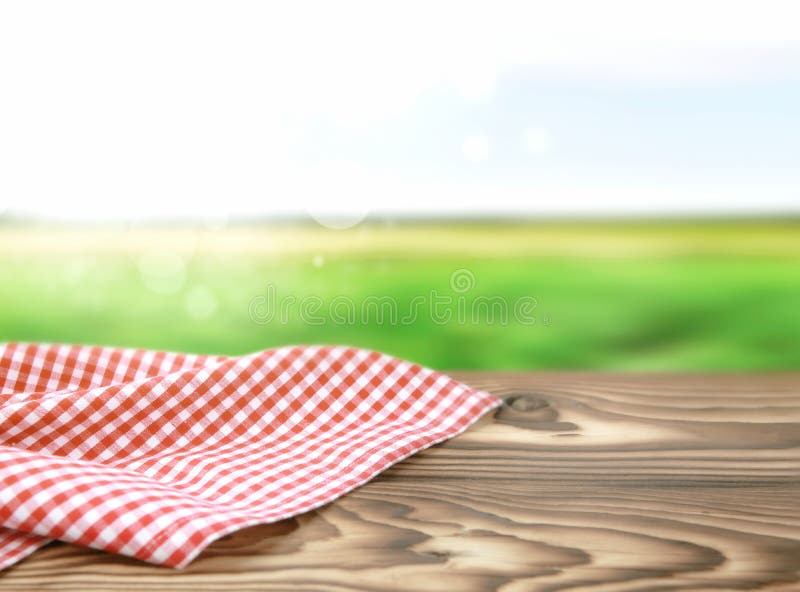 Red picnic cloth on wooden table nature blurred background.Food advertisement backdrop. Red picnic cloth on wooden table nature blurred background.Food advertisement backdrop