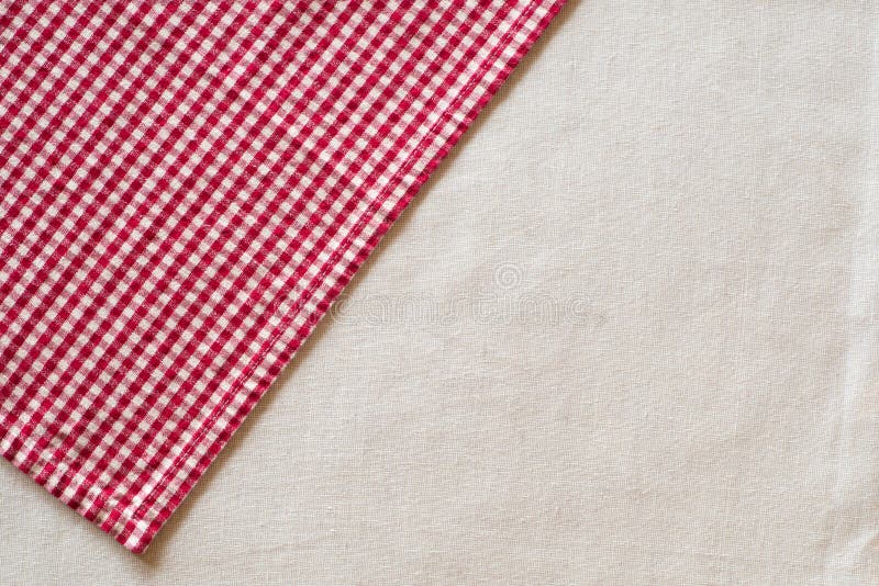 Red and White Checked Cloth at angle on upper corner of off white or cream colored linen table cloth. Horizontal above view with room or space for copy, text or your words or design. Red and White Checked Cloth at angle on upper corner of off white or cream colored linen table cloth. Horizontal above view with room or space for copy, text or your words or design