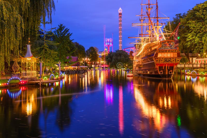 COPENHAGEN, DENMARK - SEPTEMBER 15, 2013: Tivoli Gardens at twilight. The amusement park is the second oldest in the world. COPENHAGEN, DENMARK - SEPTEMBER 15, 2013: Tivoli Gardens at twilight. The amusement park is the second oldest in the world.