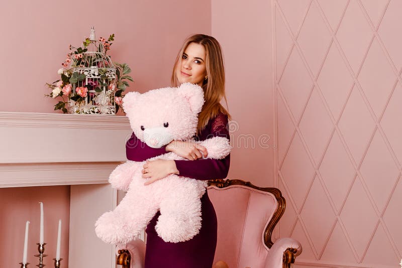 Tjugo-år-gammal kvinna i en Bourgogneklänning som rymmer en stor rosa nallebjörn royaltyfria foton Tjugo-år-gammal kvinna i en Bourgogneklänning som rymmer en stor rosa nallebjörn royaltyfria foton