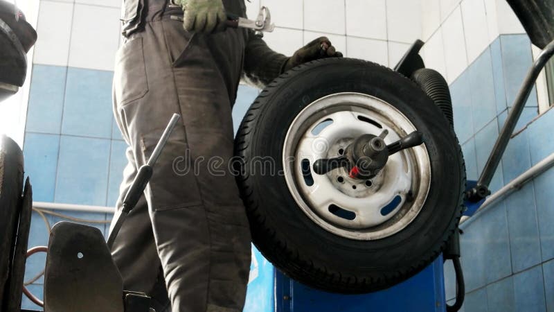 Tjänste- balansera för gummihjul av hjulet efter reparationsgummihjul, mekaniker som balanserar ett bilhjul på den automatiserade