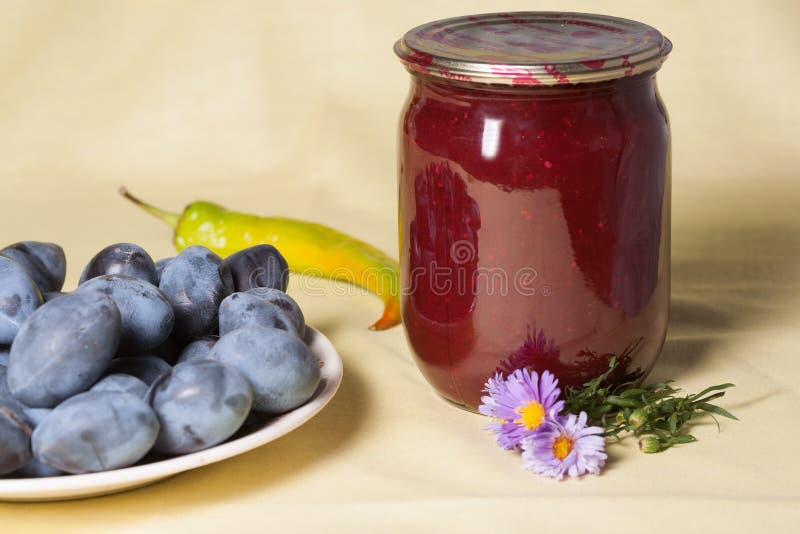 Tkemali Georgian sauce. glass jars with canned sauce. Fresh plums in a plate. stock photo Tkemali Georgian sauce. glass jars with canned sauce. Fresh plums in a plate. stock photo