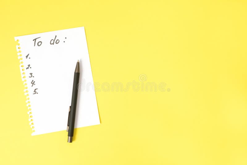 To do list on white sheet torn from spiral notebook and black pen on bright yellow table with copy space, top view 免版税库存照片 To do list on white sheet torn from spiral notebook and black pen on bright yellow table with copy space, top view 免版税库存照片