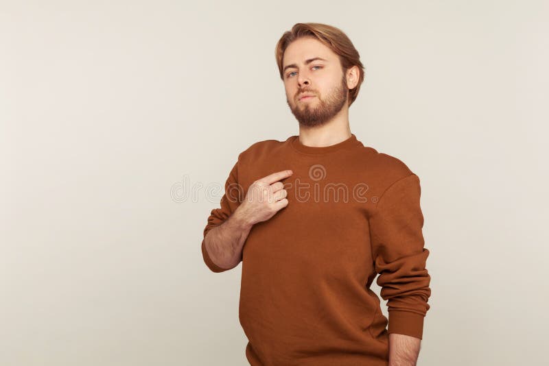 This is me! Portrait of egoistic arrogant selfish man with beard in sweatshirt pointing himself, boasting successful achievement, feeling proud and supercilious. indoor studio shot, gray background. This is me! Portrait of egoistic arrogant selfish man with beard in sweatshirt pointing himself, boasting successful achievement, feeling proud and supercilious. indoor studio shot, gray background