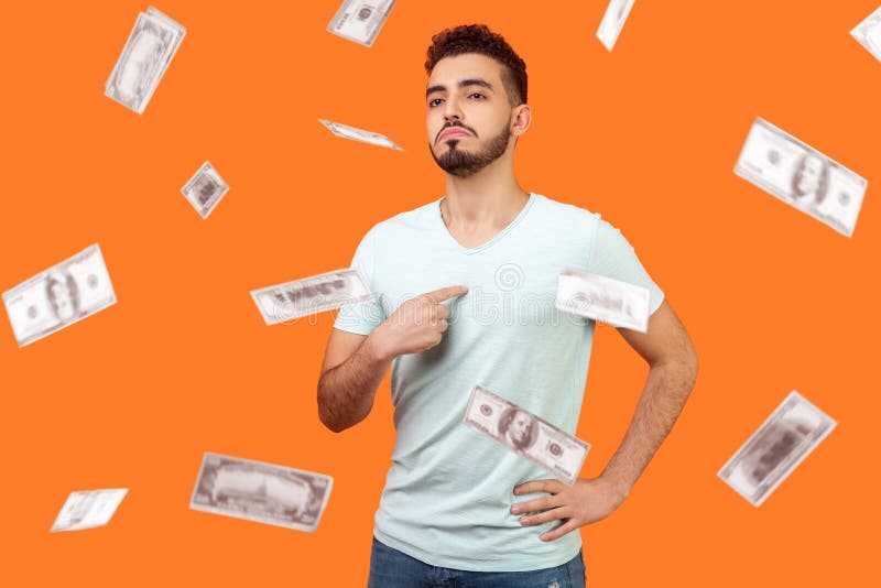 This is me, dollar millionaire! Portrait of arrogant self-confident man pointing at chest, looking proud and egoistic. money falling and he is rich. indoor studio shot isolated on orange background. This is me, dollar millionaire! Portrait of arrogant self-confident man pointing at chest, looking proud and egoistic. money falling and he is rich. indoor studio shot isolated on orange background