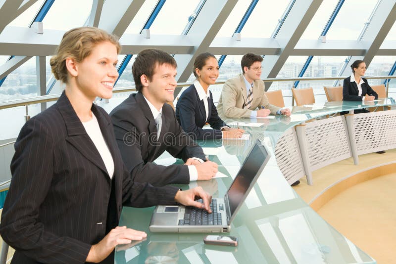 Businesspeople sitting at the round table in large light conference hall with glassy walls discussing important questions. Businesspeople sitting at the round table in large light conference hall with glassy walls discussing important questions