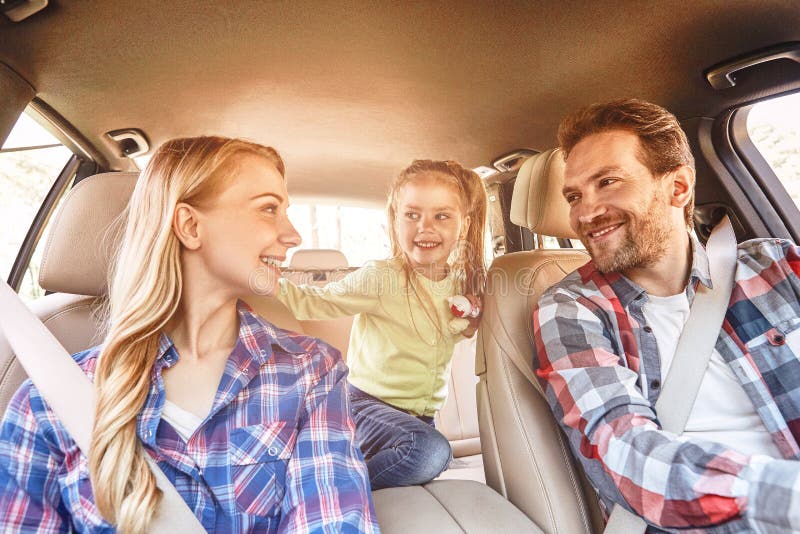 Beautiful family of three enjoying driving a car and going on road trip. Couple wearing checkered shirts. Front view. Filtered image. Beautiful family of three enjoying driving a car and going on road trip. Couple wearing checkered shirts. Front view. Filtered image