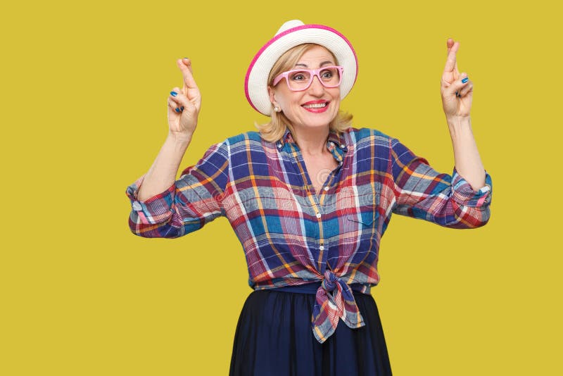 With to win. Portrait of hopeful pleased modern stylish mature woman in casual style with hat and eyeglasses standing with crossed royalty free stock photo With to win. Portrait of hopeful pleased modern stylish mature woman in casual style with hat and eyeglasses standing with crossed royalty free stock photo