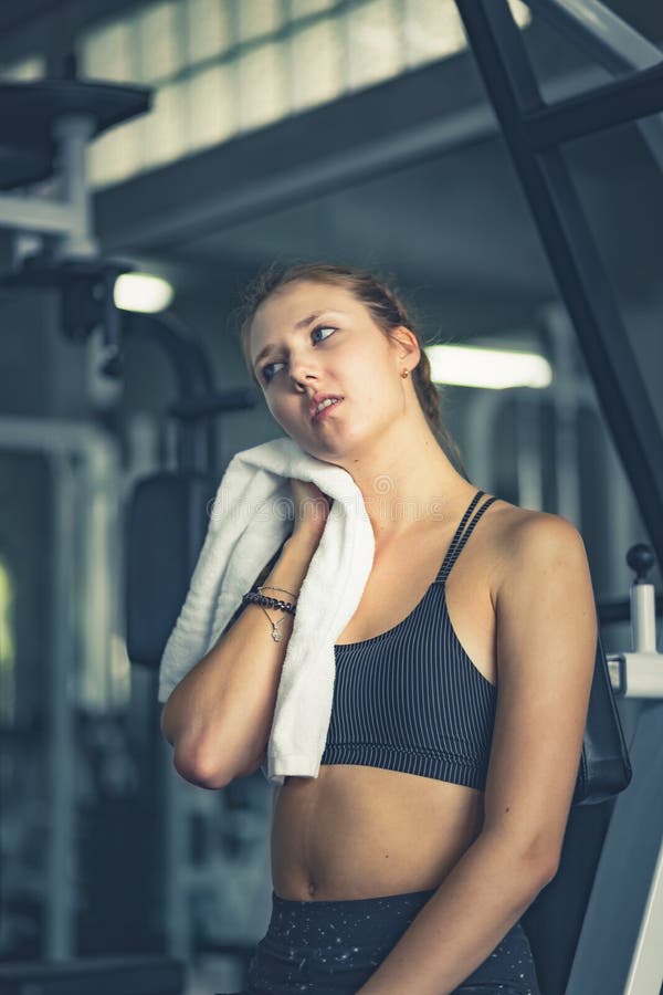 Toalha de assento da mulher atrativa nova e de utilização caucasiano para limpar o suor Abrandamento após o exercício duro no gym fotos de stock Toalha de assento da mulher atrativa nova e de utilização caucasiano para limpar o suor Abrandamento após o exercício duro no gym fotos de stock