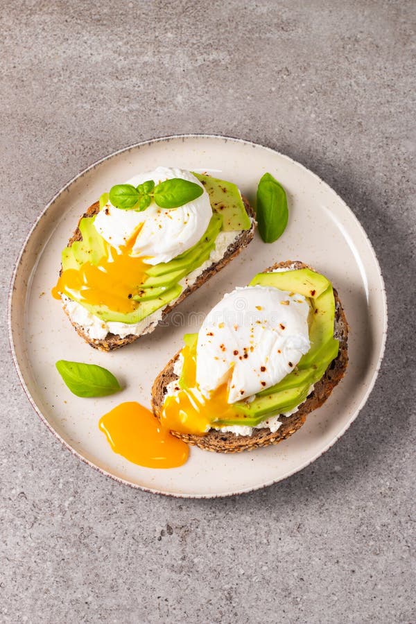 Toast with avocado, soft cream cheese, rye bread and poached Egg. royalty free stock image