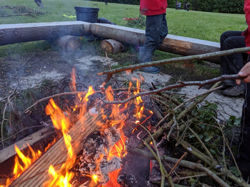 Toasting 2 marshmallows on the end of sticks over a fire