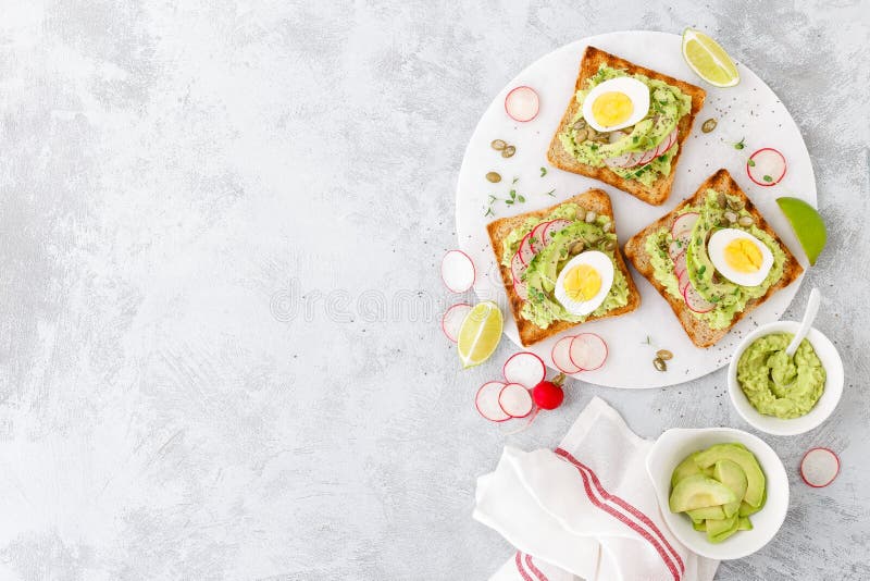 Toasts with avocado guacamole, fresh radish, boiled egg, chia and pumpkin seeds. Diet breakfast. Delicious and healthy plant-based