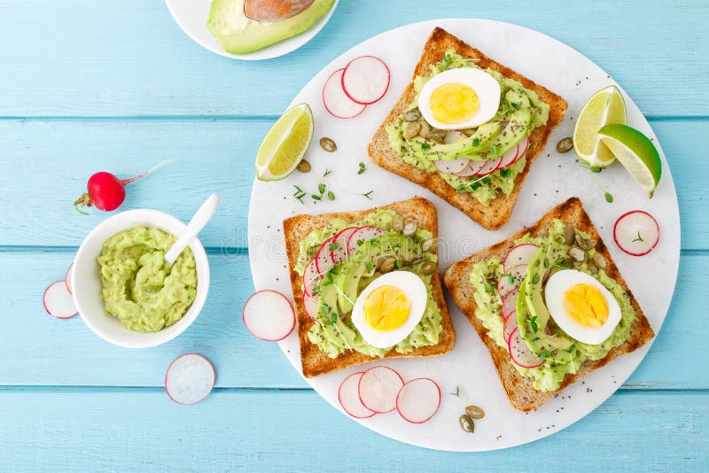Toasts with avocado guacamole, fresh radish, boiled egg, chia and pumpkin seeds. Diet breakfast. Delicious and healthy plant-based