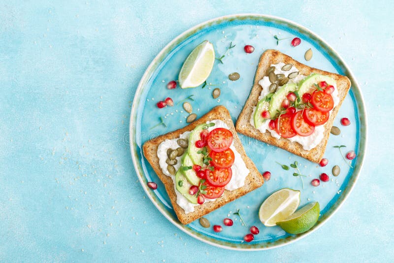 Toasts with feta cheese, tomatoes, avocado, pomegranate, pumpkin seeds and flaxseed sprouts. Diet breakfast. Delicious and healthy