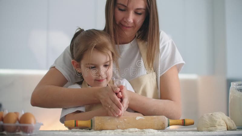 Tochter und Mutter zu Hause in der Küche in den Schutzblechen Gießen Mehl vorsehen, mit einem Nudelholz und modellieren Teig mit stock video footage