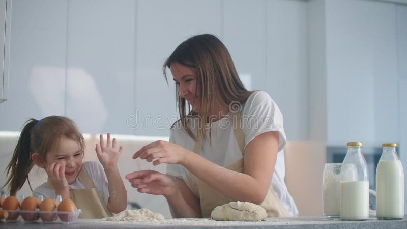 Tochter und Mutter zu Hause in der Küche in den Schutzblechen Spaß zu verfallen und geben fünf und besprühen mit Mehl stock video footage
