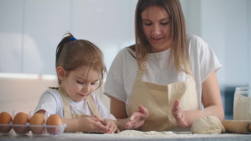 Tochter und Mutter zu Hause in der Küche in den Schutzblechen Spaß zu verfallen und geben fünf und besprühen mit Mehl stock footage