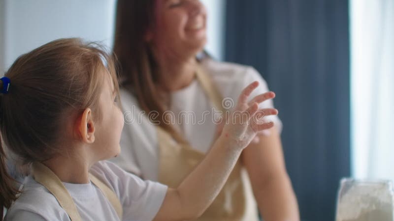 Tochter und Mutter zu Hause in der Küche in den Schutzblechen Spaß zu verfallen und geben fünf und besprühen mit Mehl stock video