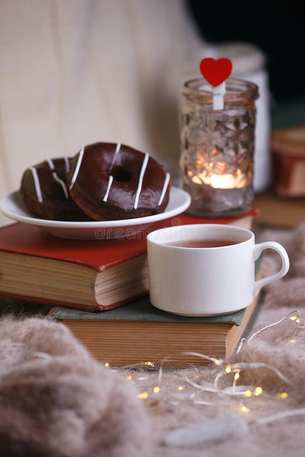 Todav?a detalles de la vida en el interior casero de la sala de estar Taza de té, de buñuelos, de libros, de tela escocesa de lan foto de archivo libre de regalías Todav?a detalles de la vida en el interior casero de la sala de estar Taza de té, de buñuelos, de libros, de tela escocesa de lan foto de archivo libre de regalías