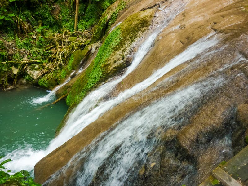 Todavía hermoso, incluso con flujo reducido en la caída temprana, se derrama a través y conecta en cascada sobre un acantilado cu foto de archivo libre de regalías Todavía hermoso, incluso con flujo reducido en la caída temprana, se derrama a través y conecta en cascada sobre un acantilado cu foto de archivo libre de regalías